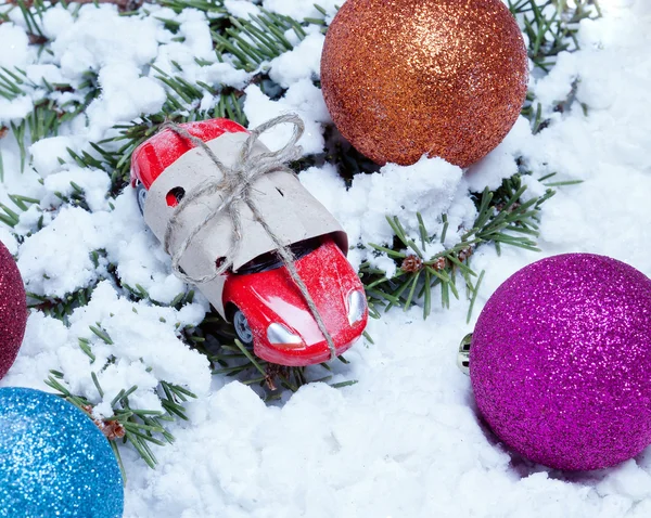 küçük oyuncak araba bir hediye ve Noel olarak topları çam dalları üzerinde Paketli