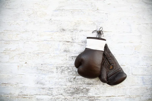 Velhas luvas de boxe penduradas em uma parede de tijolo — Fotografia de Stock