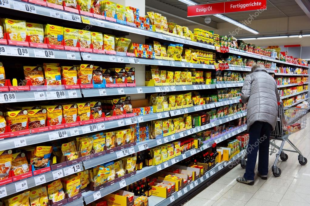 GERMANY - MARCH 2016: Customer chooses products on shelves with various of instant food packings in a REWE supermarket. The REWE Group is the second largest supermarket chain in Germany