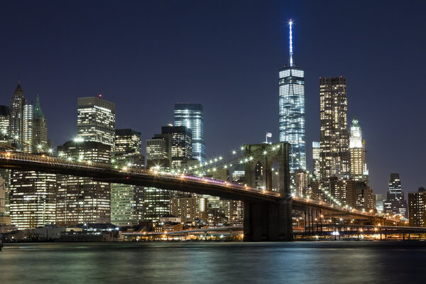 The New York City skyline at night w Brooklyn Bridge and Freedom tower