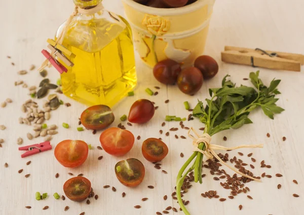 Flax seeds, tomatoes cherry and oil in bottle on wooden backgrou — Stock Photo, Image