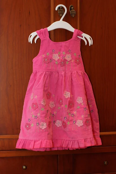 Un vestido de niña colgando en una tienda de ropa para niños . Imagen De Stock