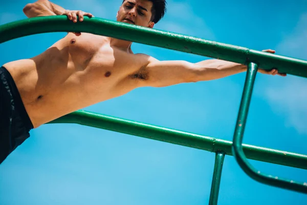 筋肉の男は屋外ジムのクロスフィットの平行棒で運動 — ストック写真