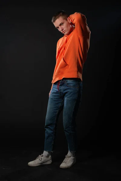 Jonge Knappe Man Jeans Oranje Hoodie Poseren Terwijl Hij Een — Stockfoto