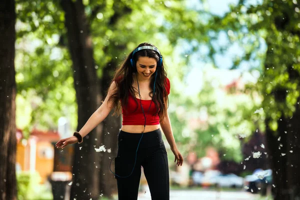 インラインスケートに乗りながら公園で楽しむヘッドフォンを持つ愛らしい女の子 — ストック写真