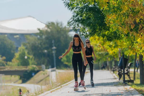 Zwei Schöne Sportlerinnen Beim Rollschuhlaufen Park Einem Sonnigen Tag — Stockfoto