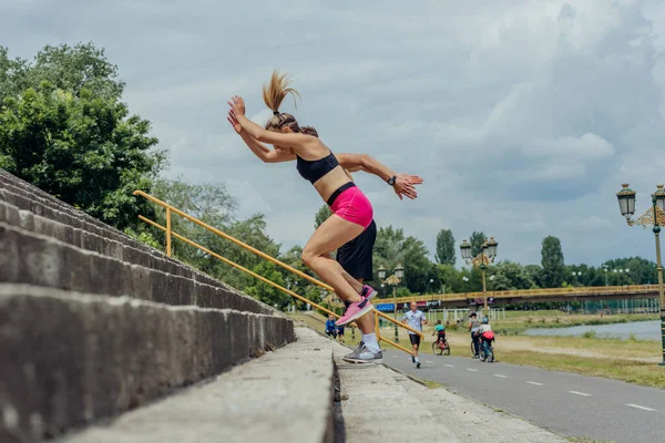 公園の階段を駆け上がるアクティブなスポーティーなカップルのサイドビュー写真 — ストック写真