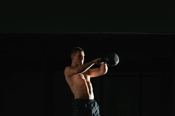 High contrast photo of a healthy fitness guy doing workout using a kettlebell