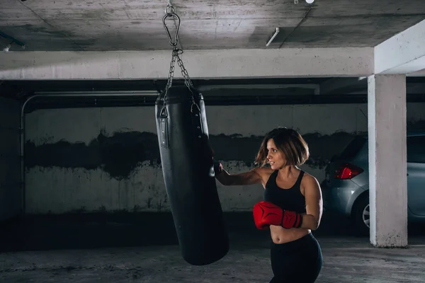 Visão Perfil Uma Jovem Forte Perfurando Saco Boxe Dentro Garagem — Fotografia de Stock