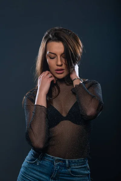 ジーンズと輝く透明シャツに身を包んだ魅力的な女性モデルの官能的なポートレート — ストック写真