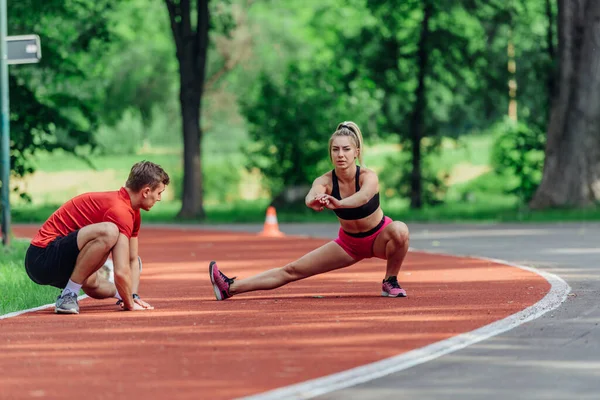 Pareja Joven Estirándose Antes Comenzar Rutina Jogging Matutino Una Pista — Foto de Stock