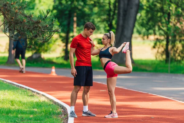 Joven Atleta Masculino Apoyando Joven Pareja Femenina Mientras Ella Estira — Foto de Stock