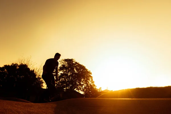 日落时分 年轻男子在当地的滑板公园练习滑板 — 图库照片