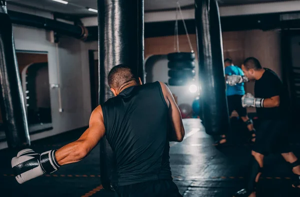 Silný Kickboxer Muž Punching Černý Sáček Písku Pozadí Posilovny — Stock fotografie