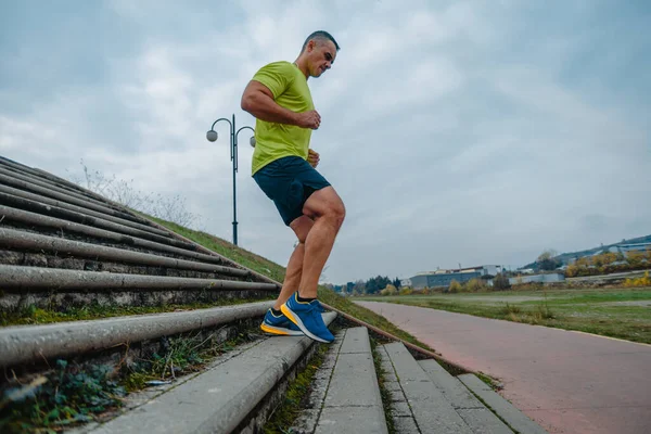 Mature man in good shape running down stairs at the local park