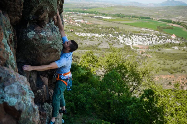 男は美しい山の風景を背景に岩に登る — ストック写真