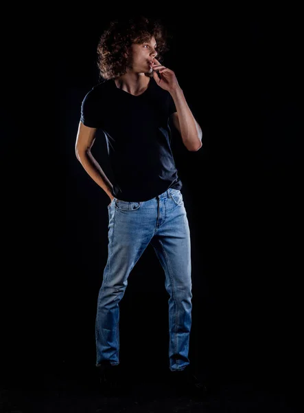 黒のTシャツの青いジーンズとスニーカーを身に着けているスタイリッシュなファッション男 — ストック写真