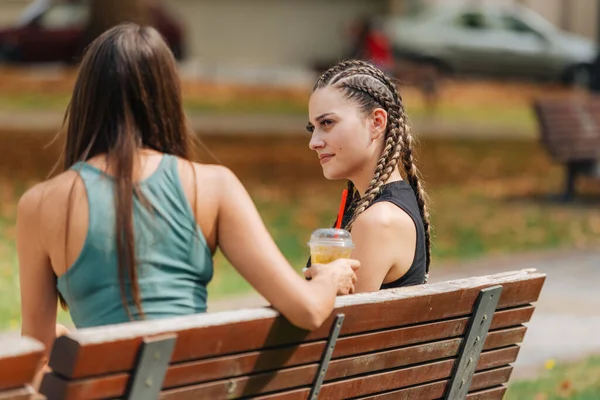 公園のベンチに座って 晴れた日に話し合っている二人の女の子 — ストック写真