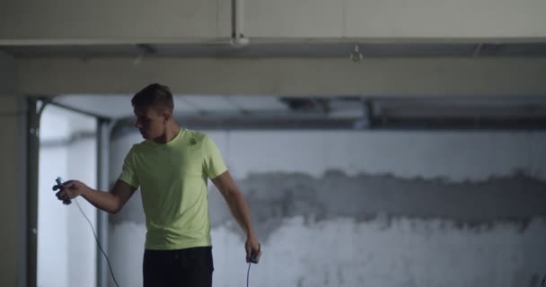 若い男練習でジャンプロープでガレージ内 — ストック動画