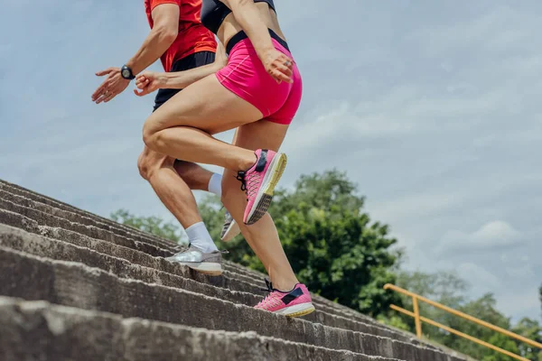 Close up and low below angle view photo of athletes legs running up concrete stairs