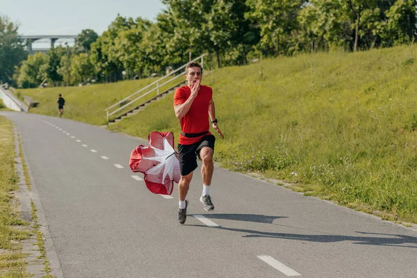 Atleta Masculino Vestindo Uma Camiseta Vermelha Está Correndo Com Paraquedas — Fotografia de Stock