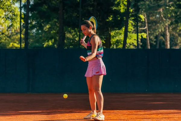 若い女性のテニス選手は テニスの試合が始まるのを待っている間にラケットで地面にボールを打つ — ストック写真