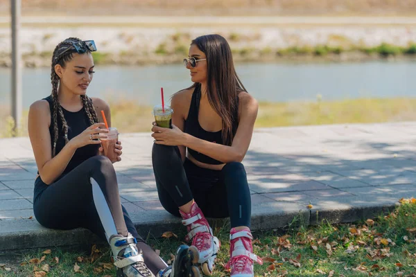 Duas Garotas Sentam Parque Enquanto Fazem Uma Pausa Patinar Bebendo — Fotografia de Stock