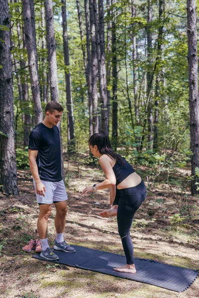 美しい若いフィットネスカップルが森の中を走る前にストレッチの準備をしています — ストック写真