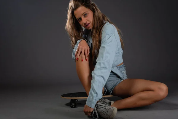 Привлекательная Девушка Фигуристка Позирует Своим Скейтбордом Изолированное Фото Студии Тёмном — стоковое фото