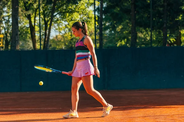 若い女性のテニス選手は テニスの試合が始まるのを待っている間にラケットで地面にボールを打つ — ストック写真