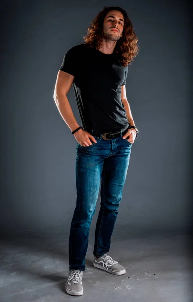 青のパンツと黒のTシャツに身を包んだ魅力的な若い男性モデル — ストック写真