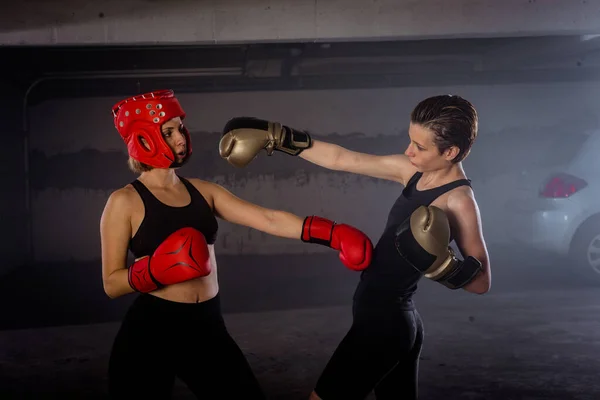 2つのプロの女性ボクサーパンチングお互いに積極的なガレージボクシングの戦いで — ストック写真