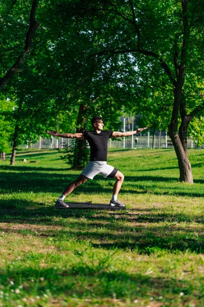 魅力的なCaucasian若いです男ストレッチとやってヨガ演習で緑の芝生の上で公園 — ストック写真