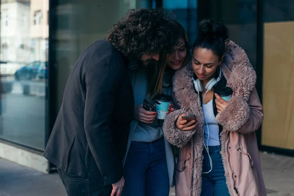 Τρεις Φίλοι Κοιτάζουν Ένα Τηλέφωνο Ενώ Στέκονται Μαζί Και Κρατάνε — Φωτογραφία Αρχείου