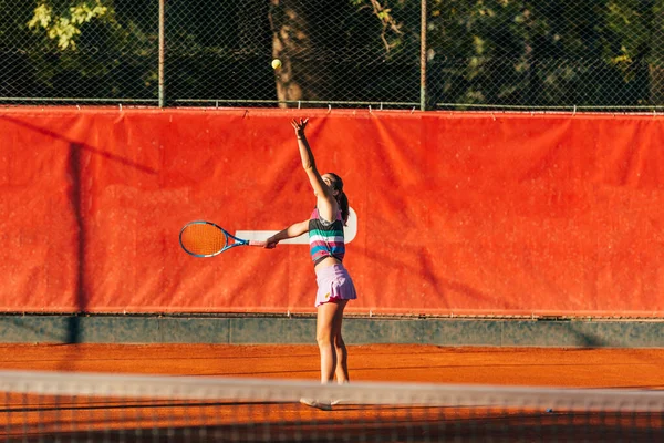 若いフィット女性は早朝にオレンジ色のテニス場でテニス屋外でプレイ — ストック写真