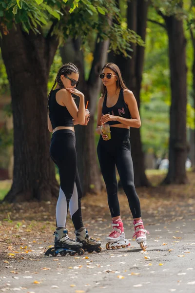 Δύο Γυναίκες Αθλητικά Κάνουν Πατίνια Στο Πάρκο Ηλιόλουστο Καιρό — Φωτογραφία Αρχείου