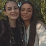 Twee vrienden praten en kijken naar hun telefoons in het park.