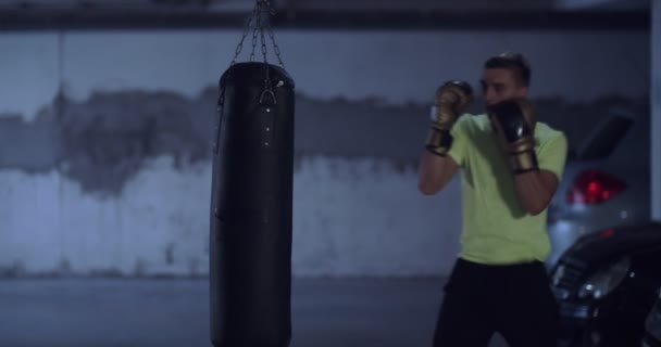 Jongeman Die Binnen Traint Met Een Bokszak — Stockvideo