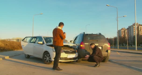 Незнакомцы Осматривающие Автомобильную Аварию Посреди Дороги — стоковое видео