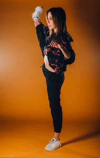 現代のオレンジ色のスタジオで激しいダンスの練習中に柔軟な運動の女の子 — ストック写真