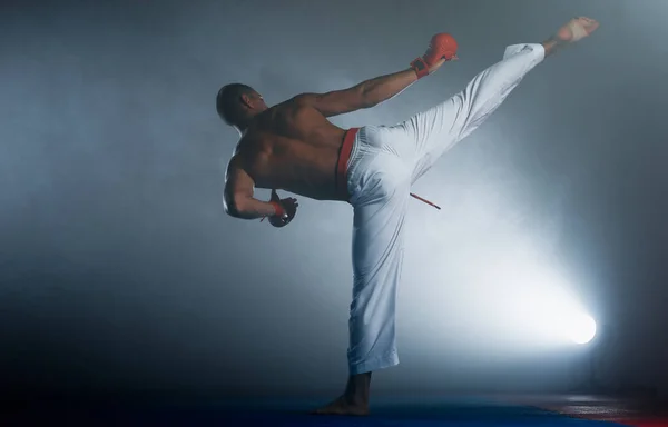 Combatiente Karate Masculino Realizando Patada Aislada Sobre Fondo Oscuro Gimnasio — Foto de Stock