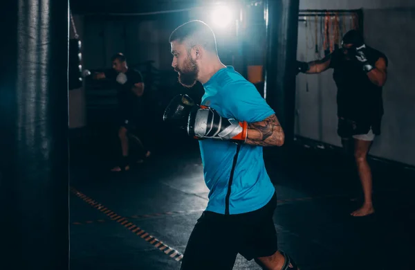 Professional muscular kick boxer training on a punching bag while preparing for the next fight