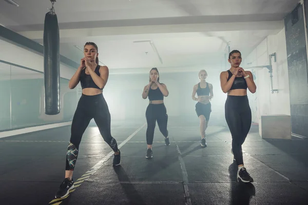 Grupo Deportistas Ropa Deportiva Haciendo Ejercicio Salto Gimnasio Con Pierna —  Fotos de Stock