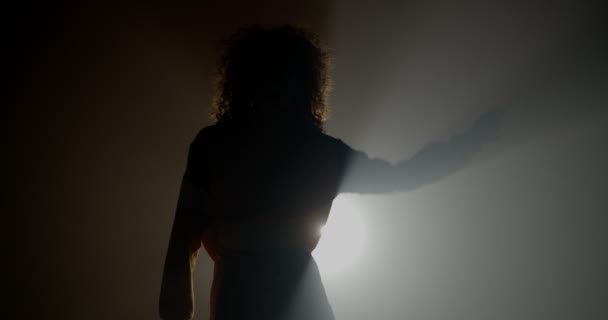 轮廓卷曲的女孩在工作室与雾和光芒跳舞 — 图库视频影像