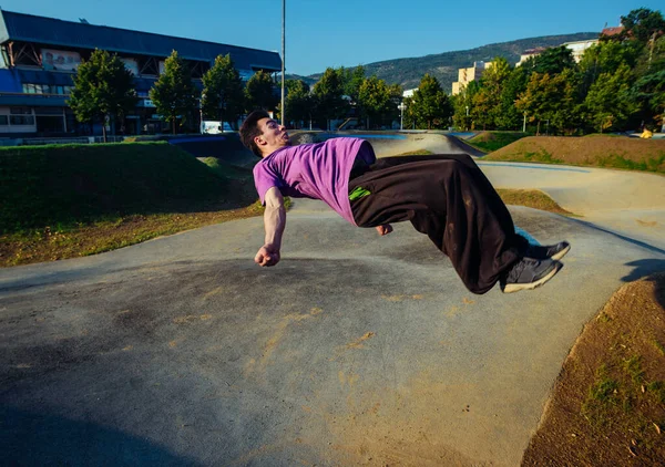 市のスケート場で空気中に移動する背もたれサルト中の運動選手 — ストック写真