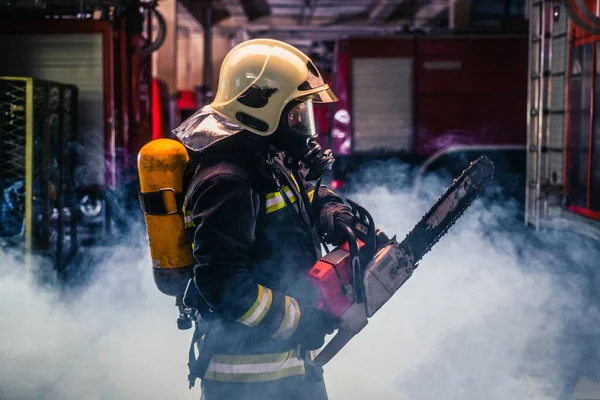 Portret Młodego Strażaka Stojącego Trzymającego Piłę Łańcuchową Środku Dymu Piły — Zdjęcie stockowe