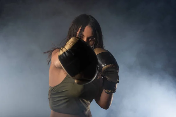 一个戴着拳击手套的女拳击手的合影 她看着带着烟熏背景的相机 — 图库照片