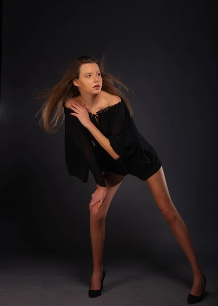 一个迷人的性感年轻女模特在深色背景下与黑色连衣裙隔离的全景照片 — 图库照片