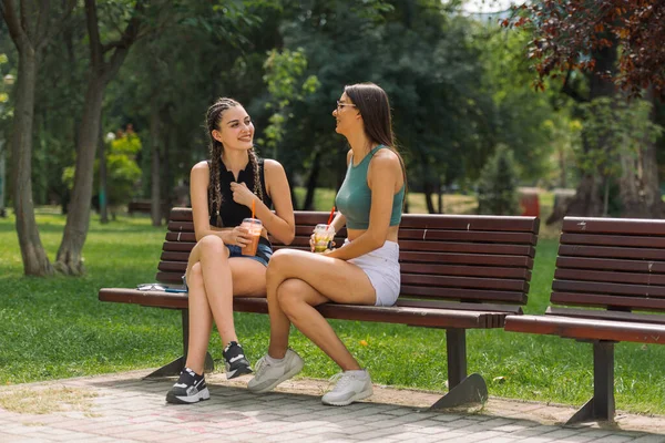 夏の公園でベンチに座っておしゃべりし 楽しい2人の若いガールフレンドのクローズアップ — ストック写真