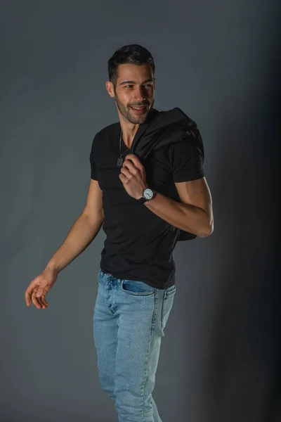 Silny Muskularny Model Męski Dżinsach Czarną Koszulką Trzymający Kurtkę Ramionach — Zdjęcie stockowe